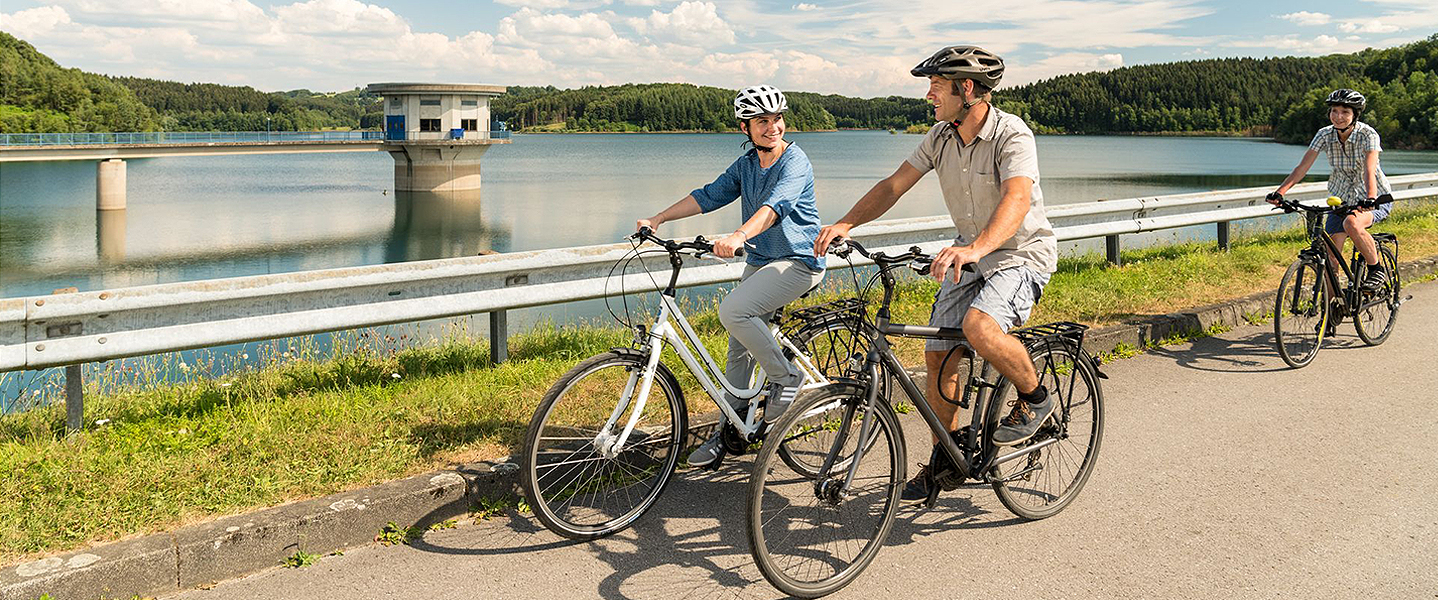 Drei Radfahrer an einem Stausee